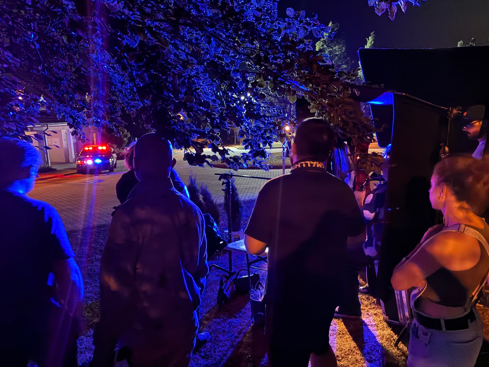 Night exterior shoot lit in blue with a police car in the background