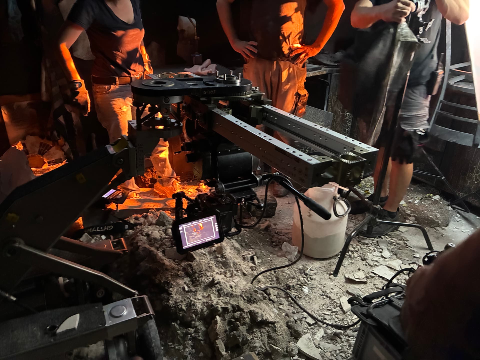 Camera crane and monitor set up in a firelit rubble interior