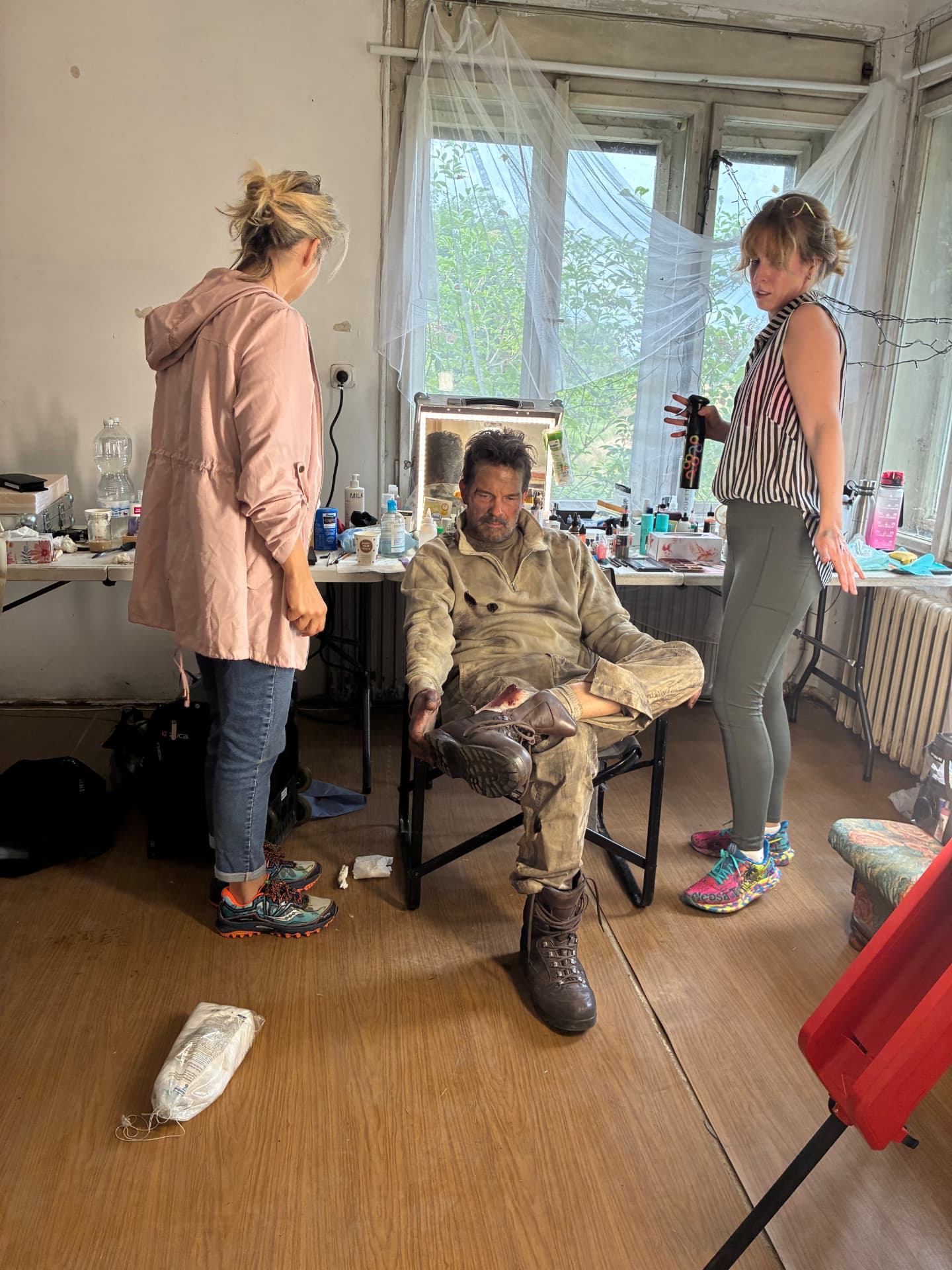 Hair and makeup team working with an actor in soot-covered costume