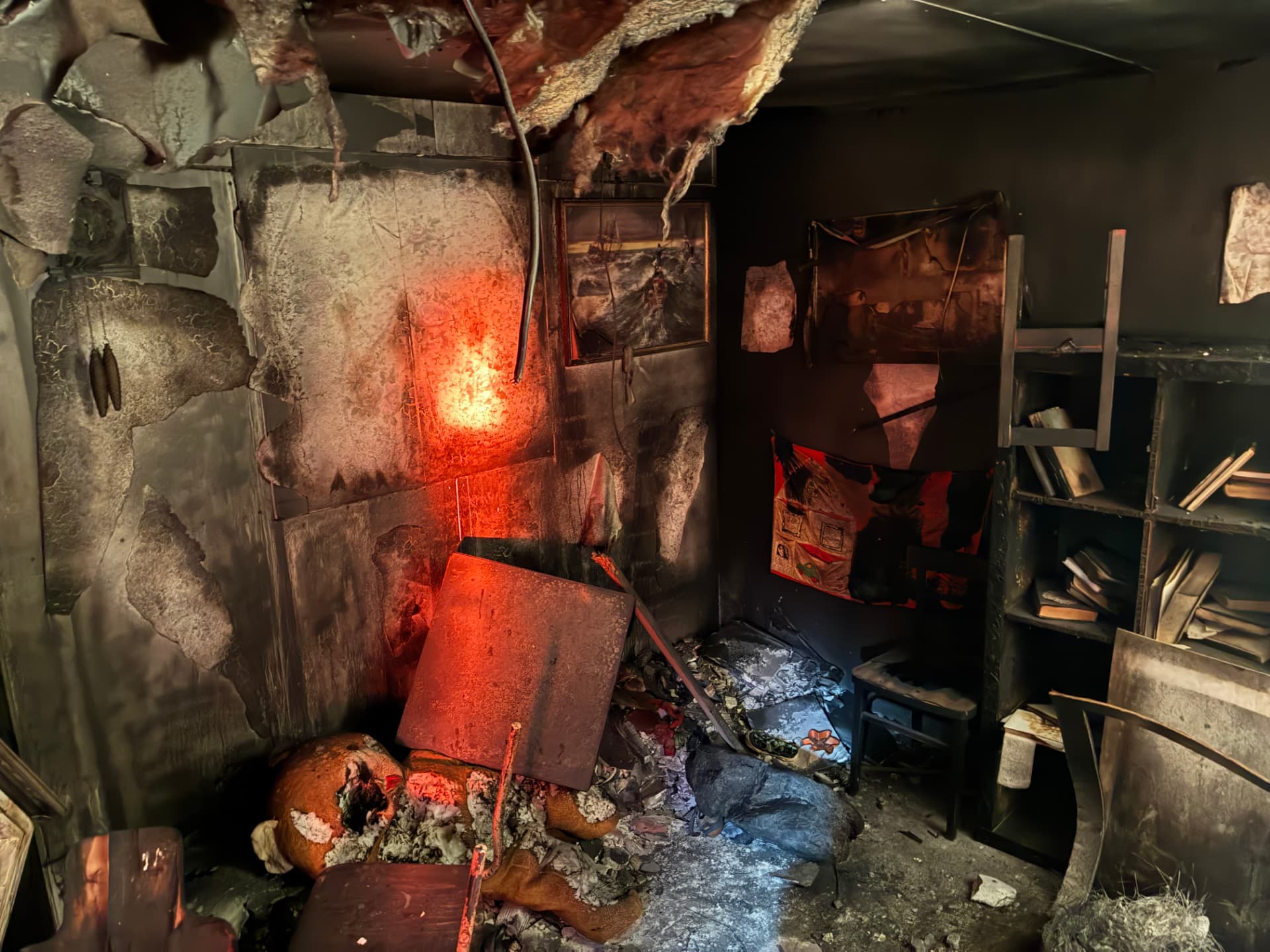 Charred bedroom set dressed with debris and scorched furniture