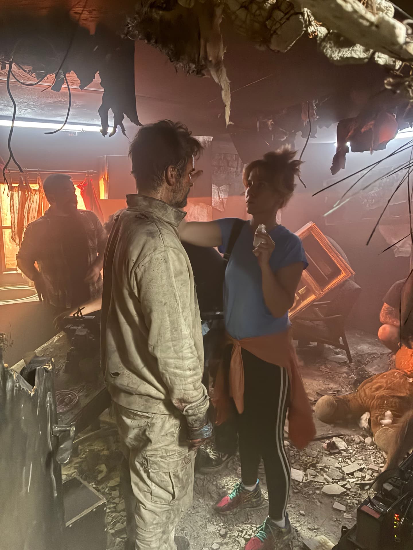 Actor in costume receiving notes on the smoke-filled apartment set